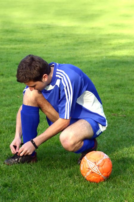 greek footballer doing his boots laces