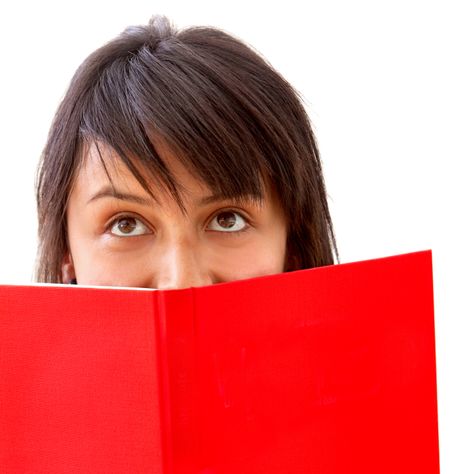 Girl covering her face with a book isolated