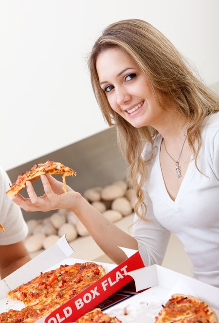 Beautiful young woman indoors eating some pizza