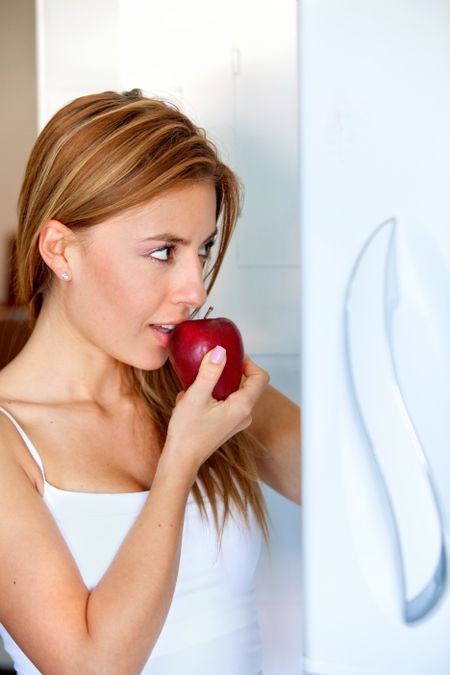 Woman at the fridge with an apple
