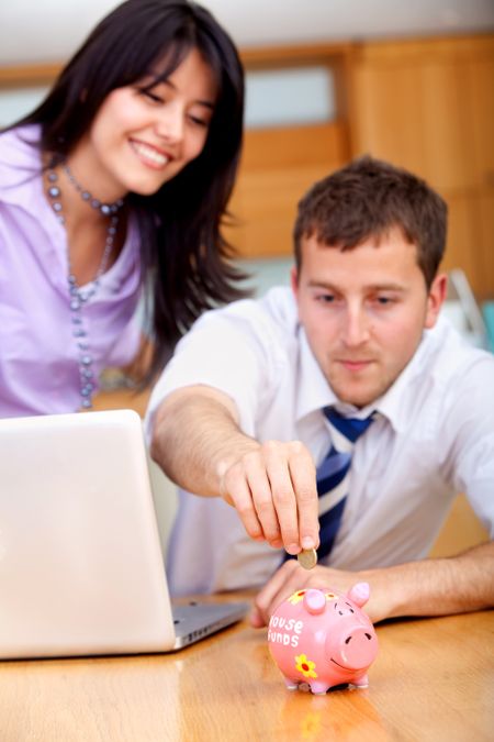 Business couple saving money into a piggy bank
