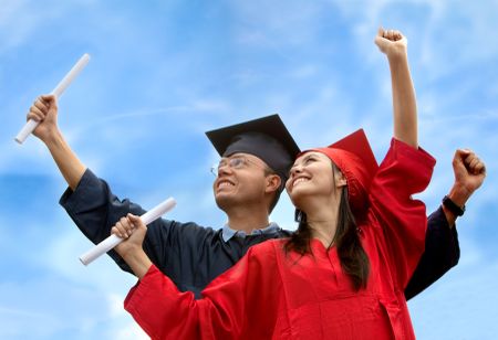 Couple of graduates with gowns and mortarboards outdoors