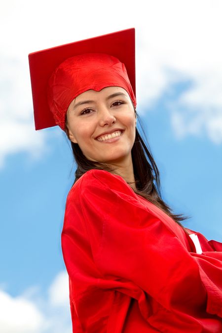 Portrait of a graduated female in a red gown outdoors