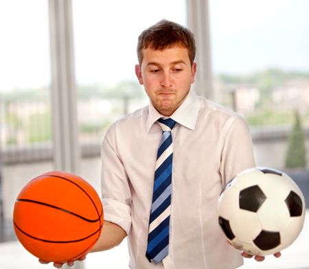 Undecided business man between basketball or football