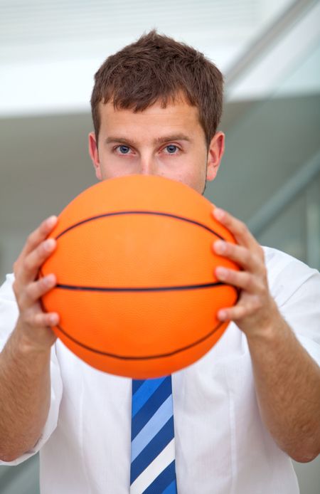 Business man covering his face with a basketball
