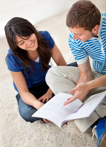 Casual friends sitting on the floor studying indoors