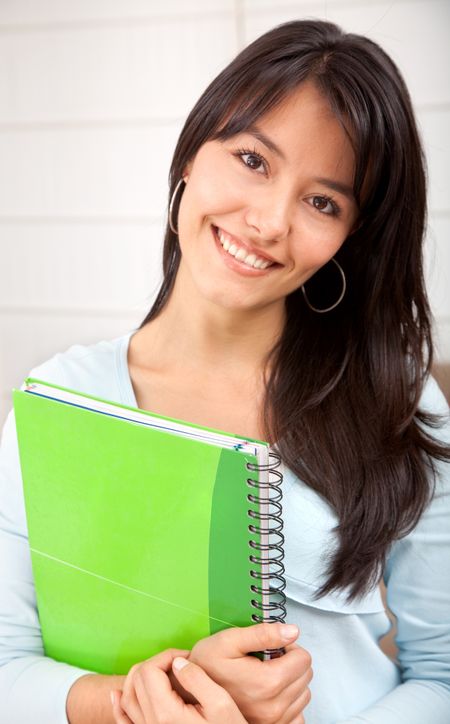 Portrait of a beautiful female student holding a notebook