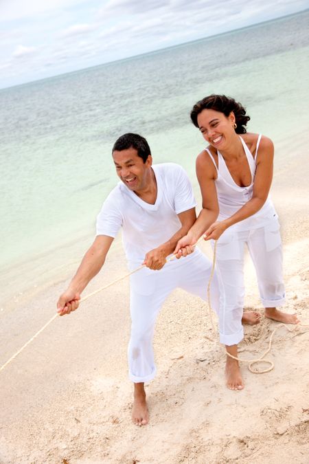 Man and woman pulling a rope at the beach