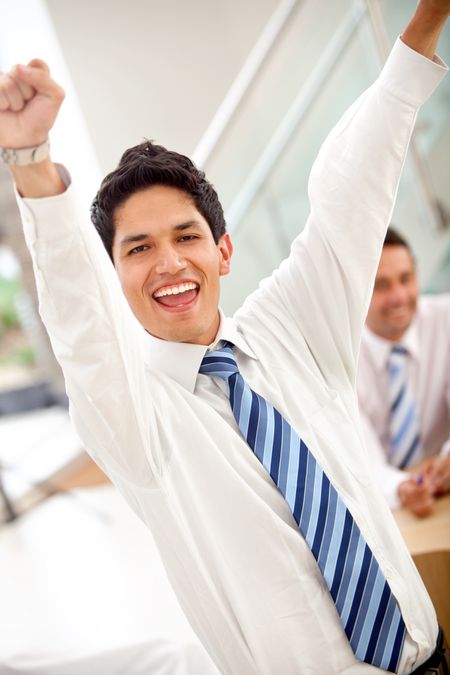 Excited business man with arms outstretched in an office