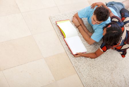 Couple lying on the floor indoors reading a book