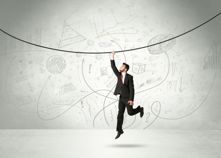 Businessman hanging on a rope with analysis and graphs background