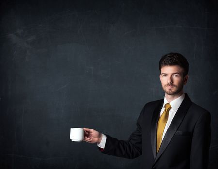 Businessman standing and holding a white cup on a black background 