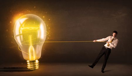 Business man pulling a big bright glowing light bulb concept on background