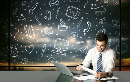 Businessman sitting at table with hand drawn social media icons and symbols 