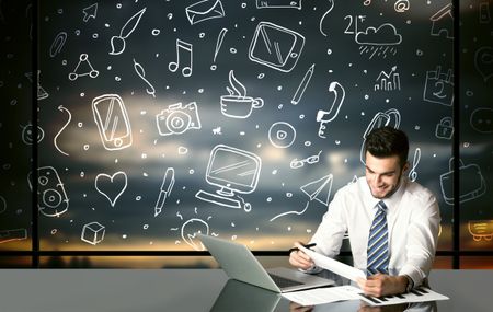 Businessman sitting at table with hand drawn social media icons and symbols