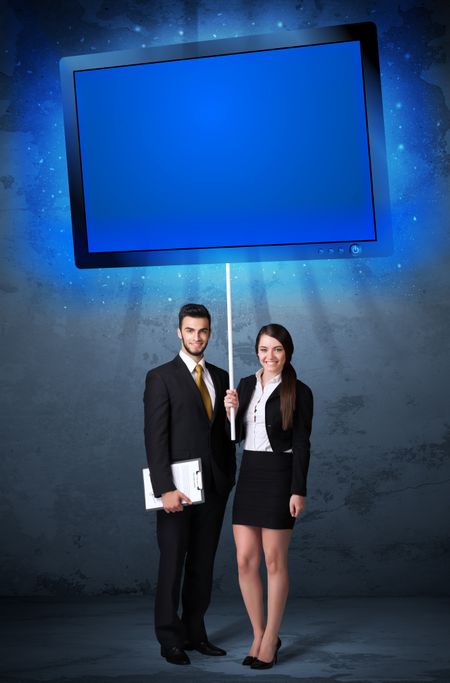 Young business couple holding a big, blue shining tablet 