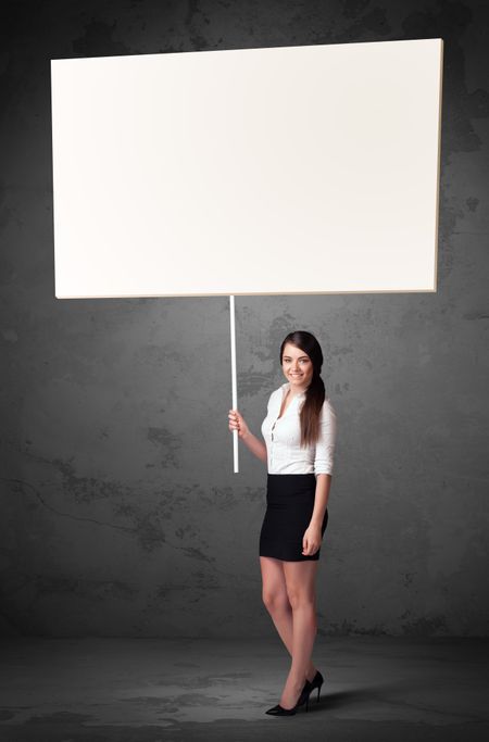 Young businesswoman holding a blank whiteboard 