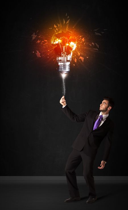 Businessman with an explosion bulb on black background