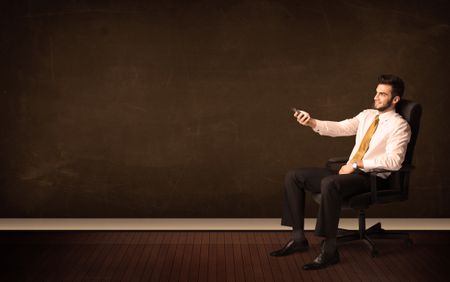 Businessman holding high tech tablet on brown background with copyspace