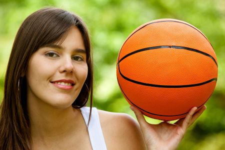 Beautiful young woman with a basketball smiling