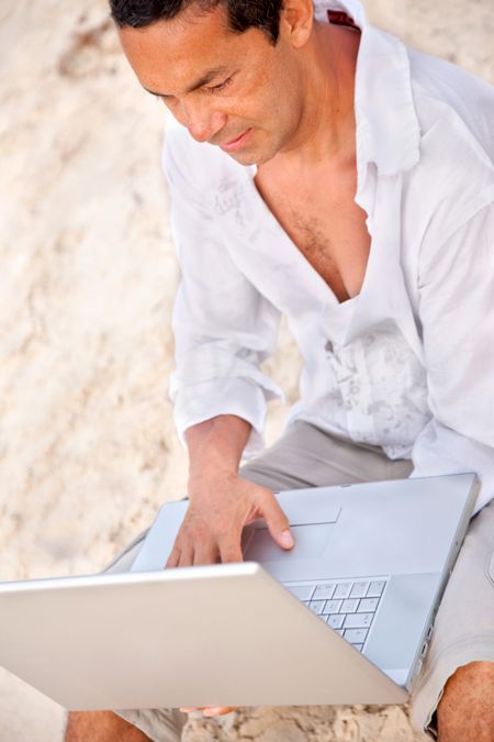 Man at the beach working on a laptop
