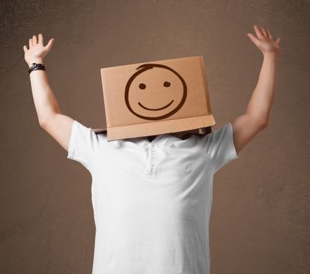 Young man standing and gesturing with a cardboard box on his head with smiley face