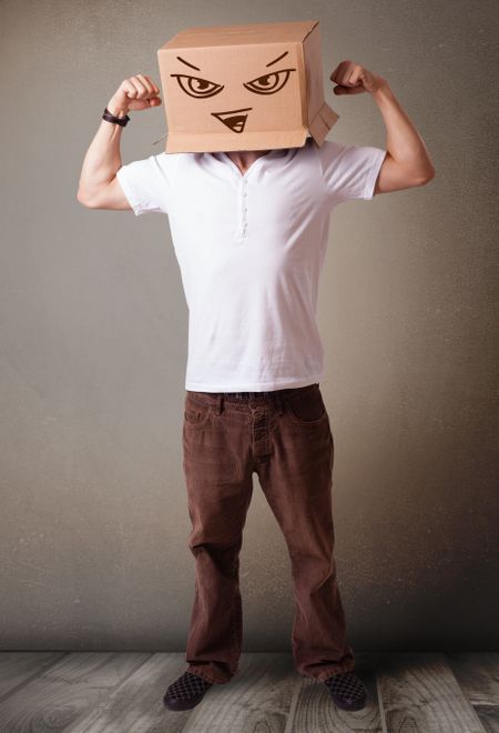 Young man standing and gesturing with a cardboard box on his head with evil face