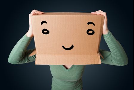 Young woman standing and gesturing with a cardboard box on her head with smiley face