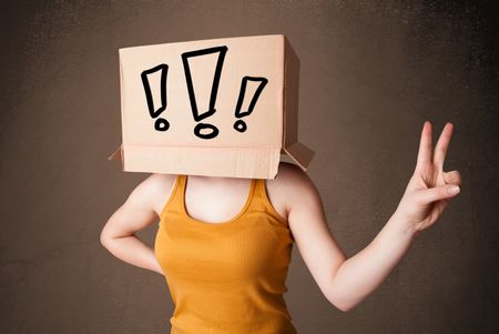 Young lady standing and gesturing with a cardboard box on her head with exclamation point