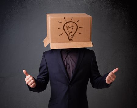 Young man standing and gesturing with a cardboard box on his head with light bulb