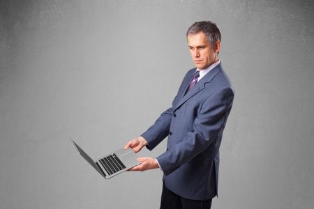 Handsome businessman in suit holding modern laptop