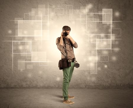 A hobby photographer with professional camera gear and belt shooting in front of brown sepia urban concrete wall full of glowing square illustrations concept