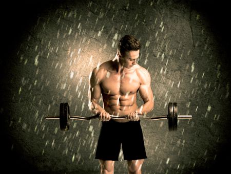 A handsome young body builder weightlifting while showing his muscular upper body in the rain concept