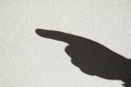 Shadow of human hand with pointing finger on whitewashed wall