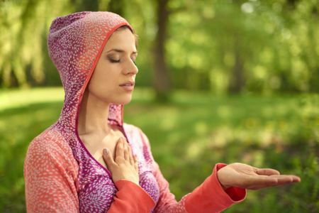 Serene and peaceful woman practicing mindful awareness mindfulness by meditating in nature at sunset