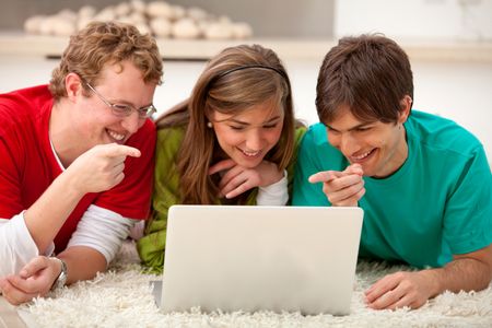 Happy group of friends with a laptop pointing at the screen