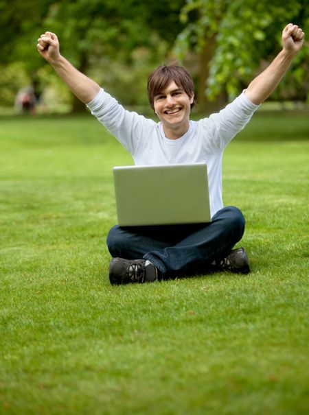 Happy young man with a laptop outdoors smiling