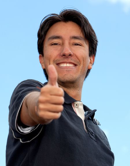 Casual man portrait smiling with thumbs-up outdoors