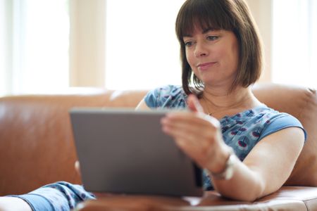 Mature woman browsing the internet on a digital tablet