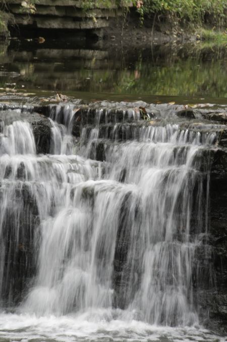 Waterfall over broken rock in river through woods