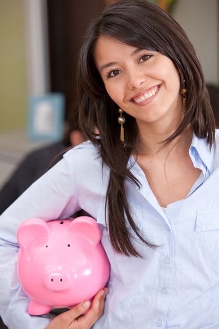 Bsuiness woman holding a piggy bank in an office