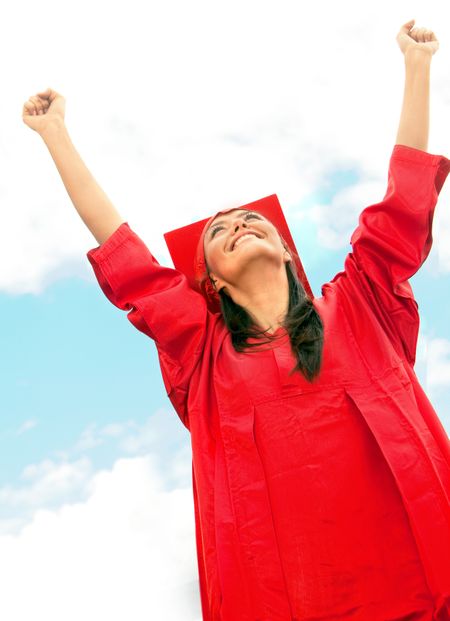 Happy graduated woman in red gown outdoors
