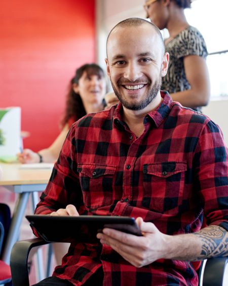 Confident male designer working on a digital tablet in red creative office space