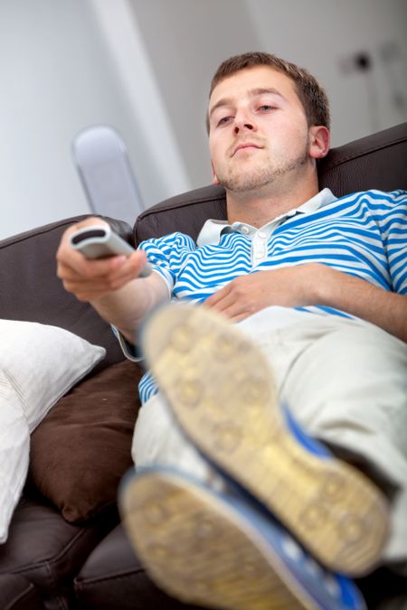 Relaxed man with a remote control watching tv
