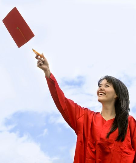 Happy graduated woman in red gown outdoors