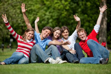 Excited group of friends with raised arms outdoors
