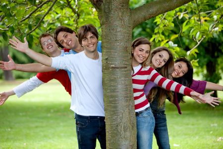 Group of friends behind a tree smiling