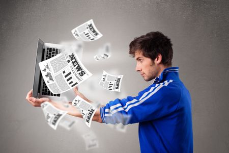 casual-young-man-holding-laptop-reading-383122303 Casual young man holding a laptop and reading the explosive news