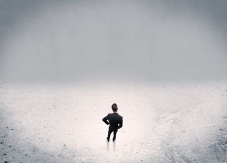 An adult elegant businessman standing in the middle of nowhere in empty grey concrete space background concept