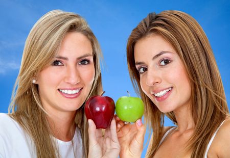 Two beautiful women with some apples isolated over blue